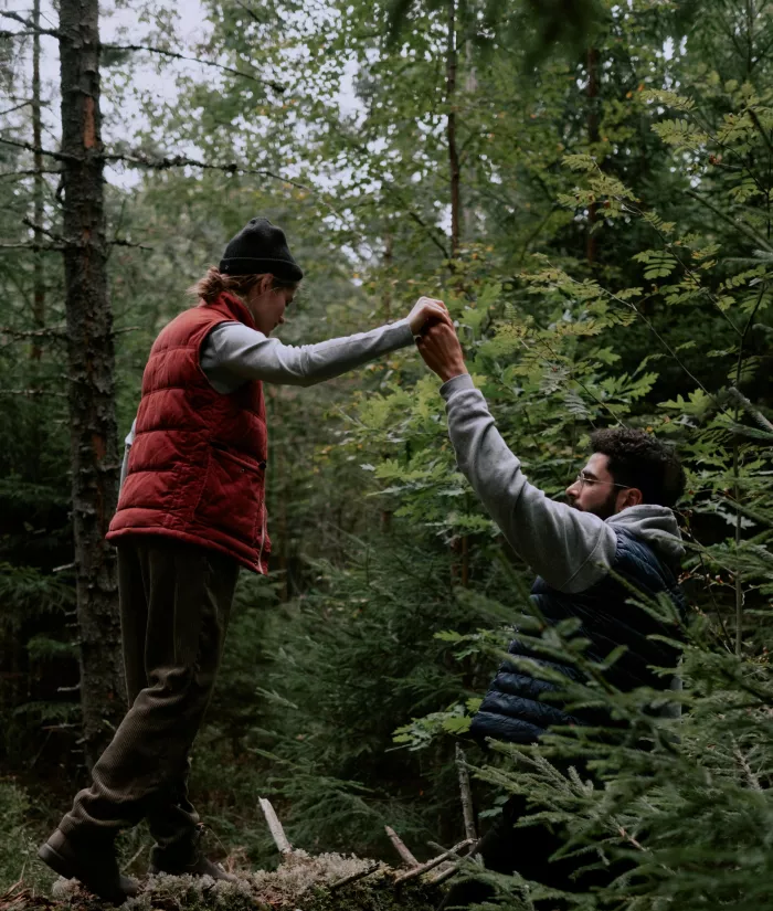 Unterstützung Zwei Menschen, die sich auf einem Weg mit Hindernissen im Wald gegenseitig helfen