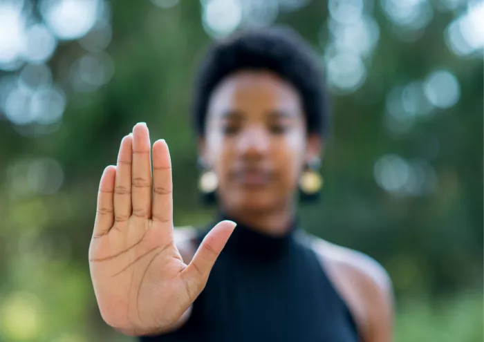 Stop Eine Frau, die durch ein Handzeichen "Stop" signalisiert.